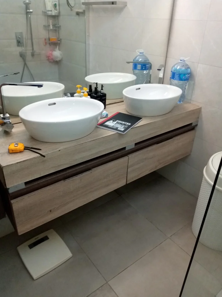 Twin sinks in a modern bathroom with organized plumbing beneath.