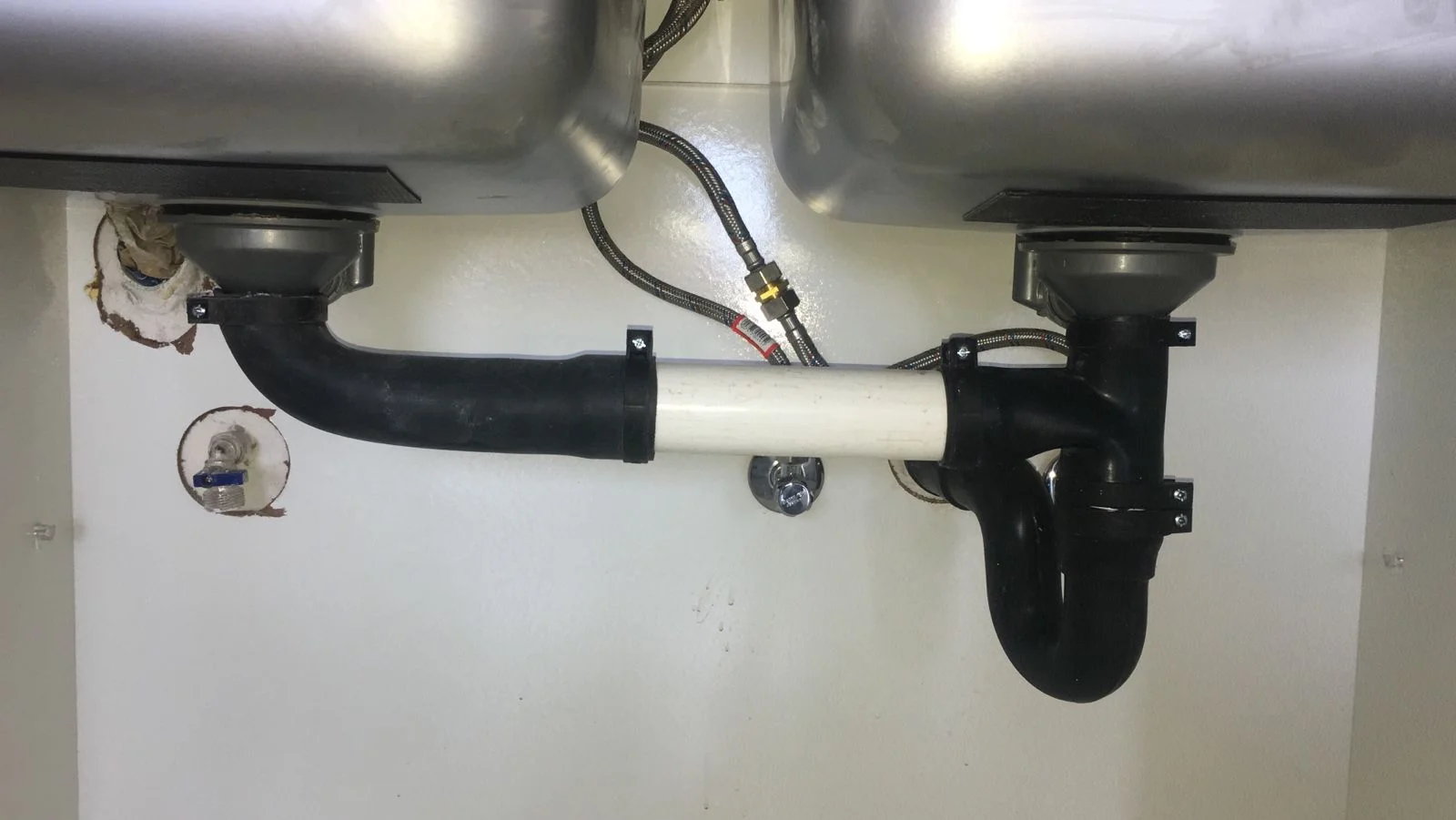 Under-sink plumbing system with newly installed pipes.