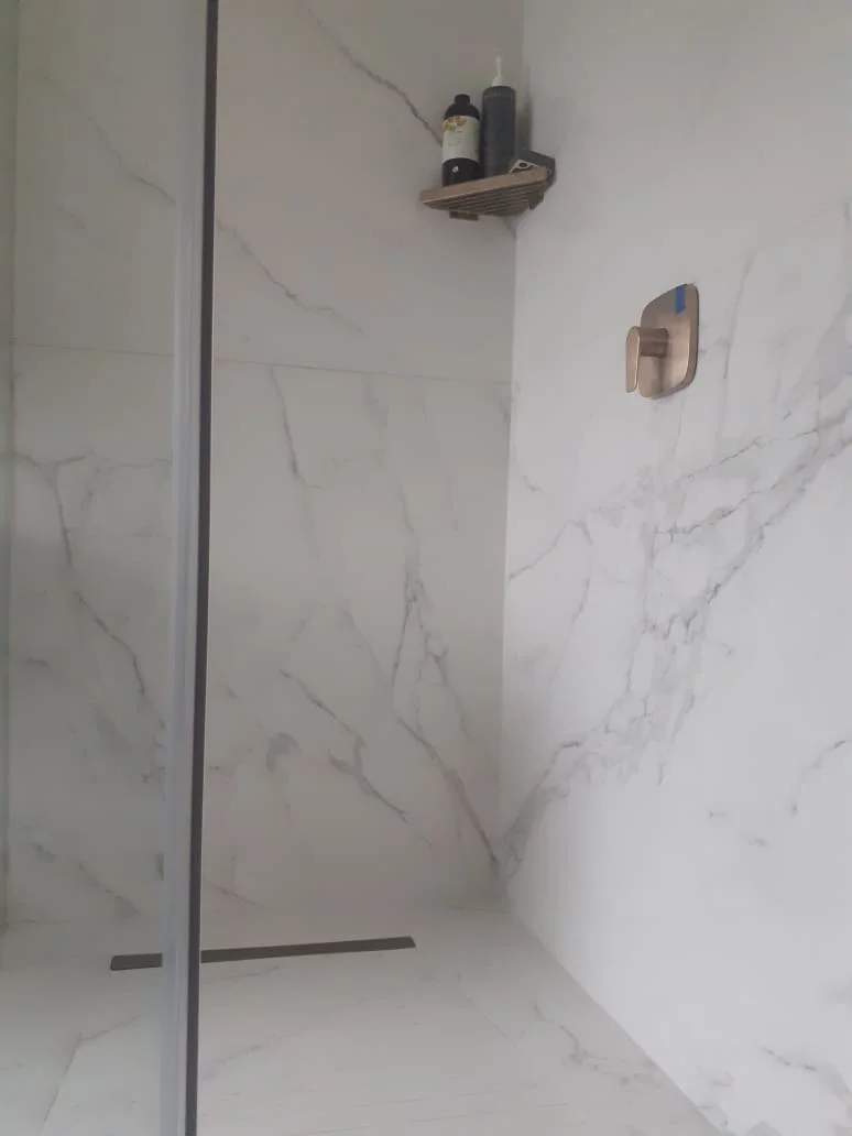 Shower installation with marble tiles and modern fixtures.