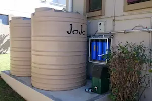 Large JoJo water tanks installed outdoors, used for water storage and management.